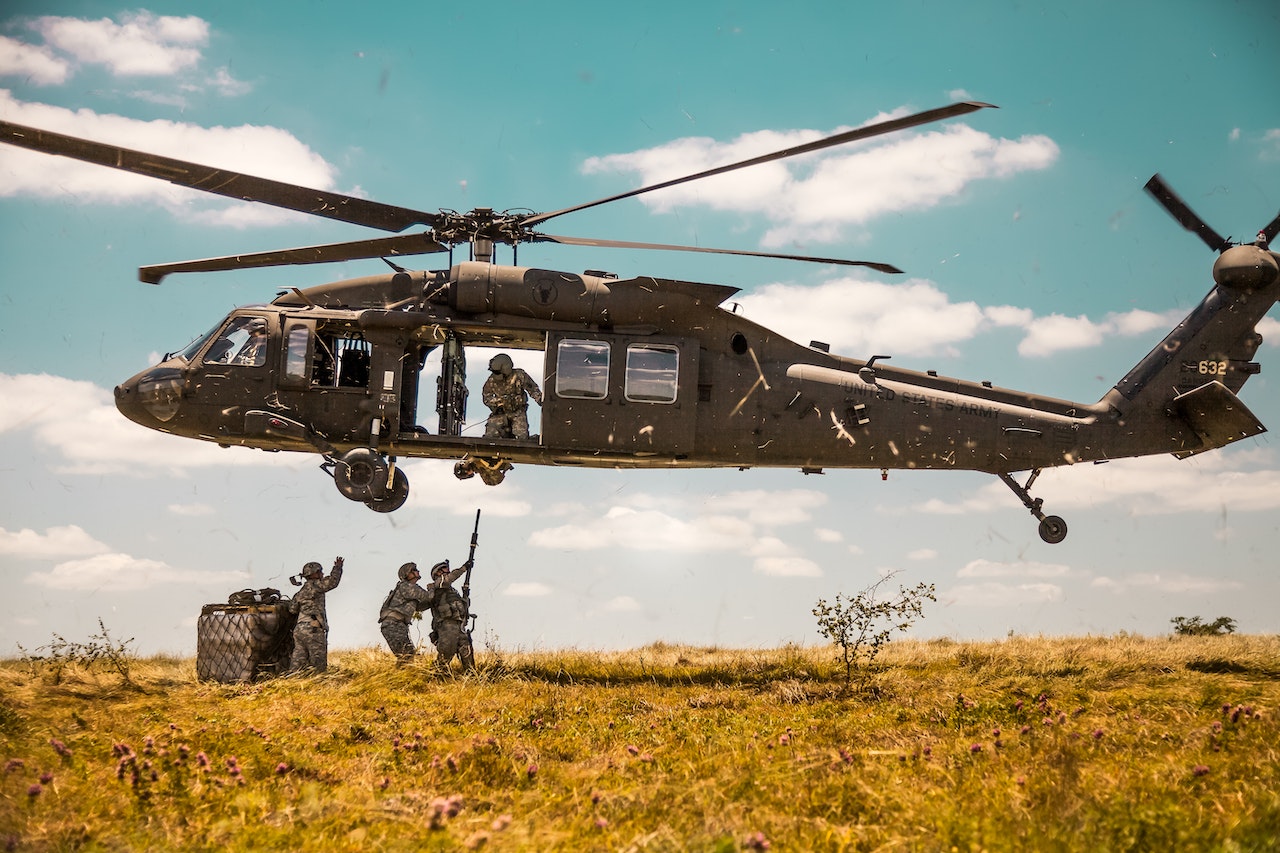 u.s. army helicopter hovering over soldiers in field