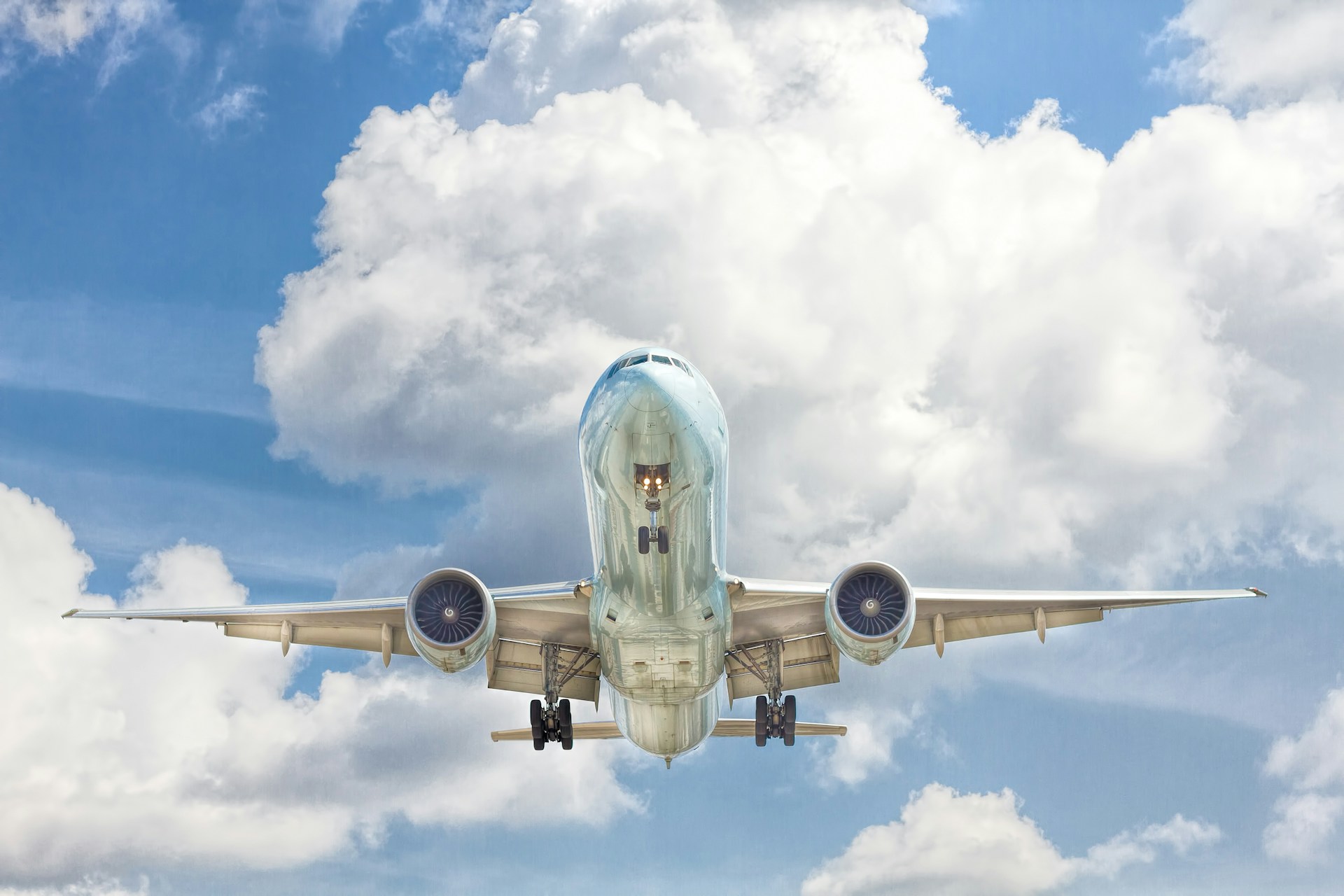 airplane flying against blue sky and clouds