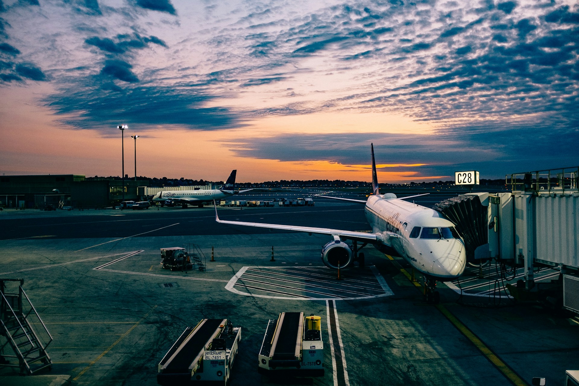An airplane on the tarmac by an airplane hanger.