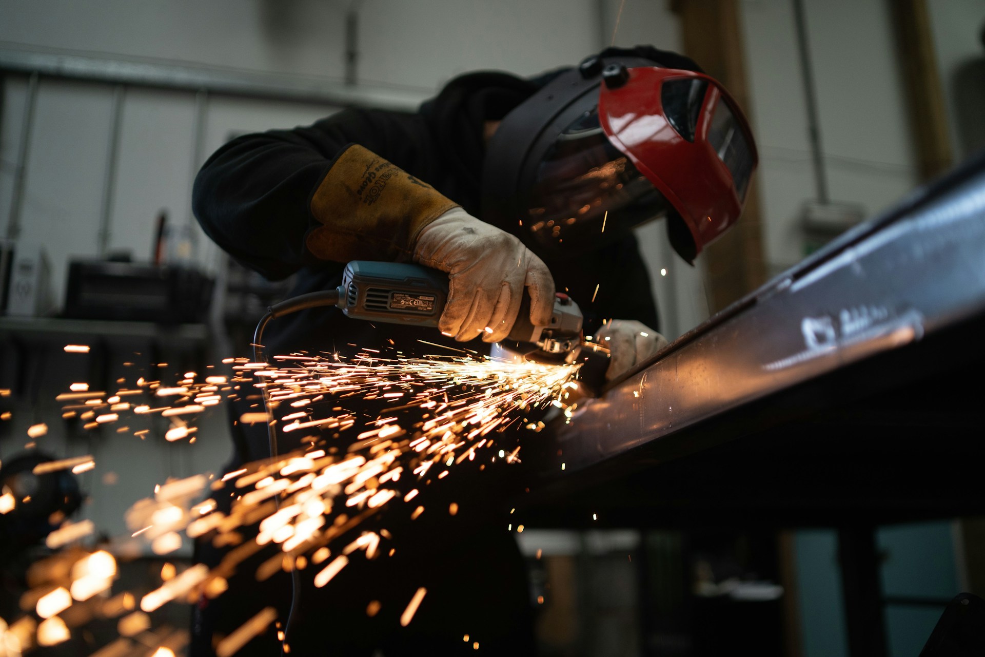 man grinding component with sparks